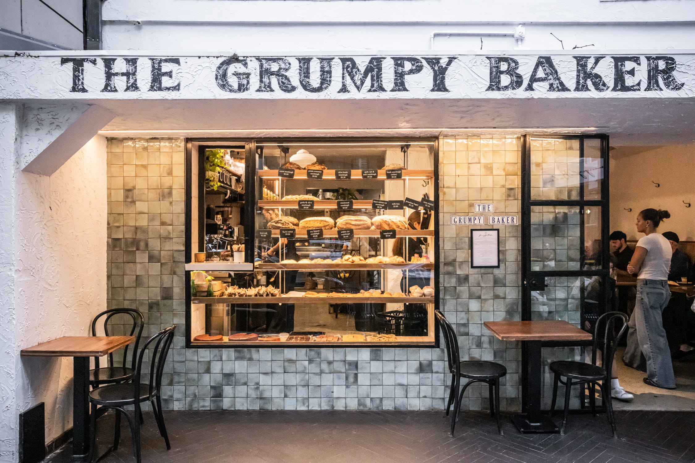 Storefront of grumpy baker Potts Point with bread in windows and people waiting